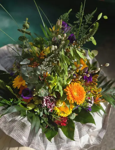 Natürlicher Wiesenstrauß mit orangefarbenen Blüten und viel Grün