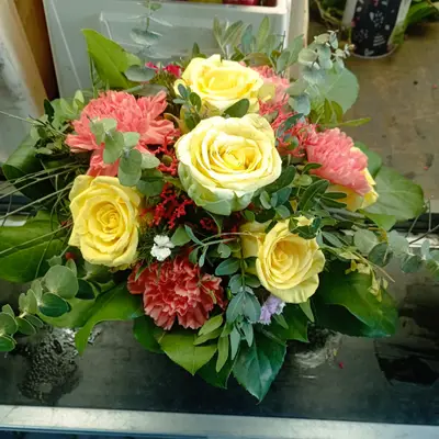 Bunter Strauß mit gelben Rosen, orangefarbenen Nelken und roten Akzenten