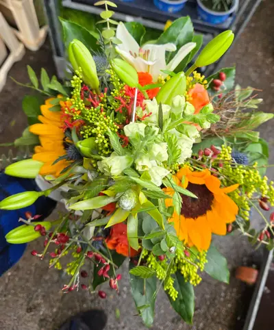Sommerlicher Strauß mit Sonnenblume, Lilien und orangefarbenen Blüten