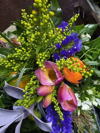 Farbenfroher Strauß mit blauem Statice, gelbgrüner Goldrute und orangefarbenen Blüten