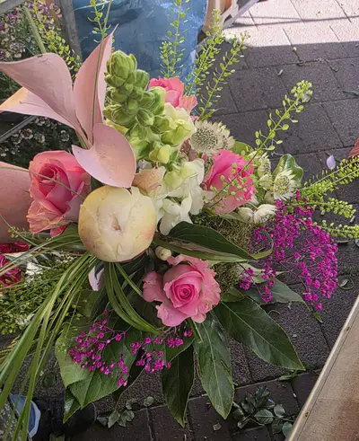 Romantischer Strauß mit rosa Rosen, weißer Blüte und dekorativem Palmblatt